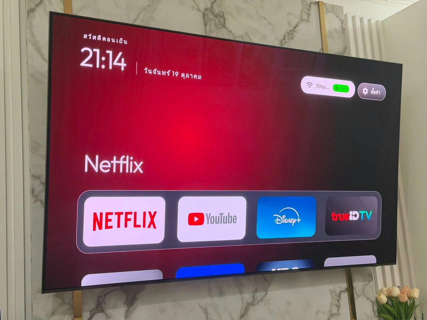 หน้าจอสมาร์ตทีวีสไตล์ Apple TV แสดงนาฬิกาและไอคอน Netflix ขนาดใหญ่